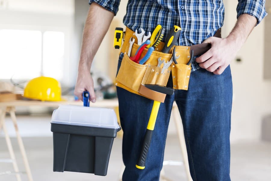A professional air conditioner technician preparing to perform maintenance on an air conditioning unit