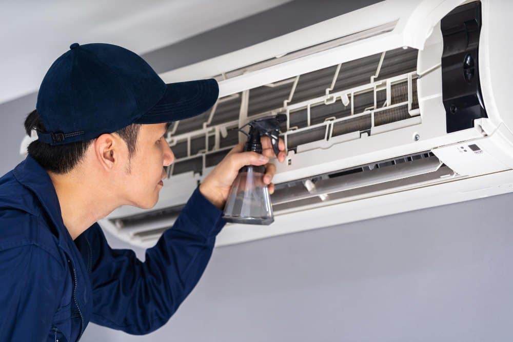 A technician servicing an air-conditioning unit during a scheduled visit.