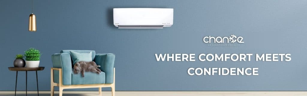 A wall-mounted indoor unit above an armchair in a blue-walled living room, with the Chance Air-Cond wordmark and the line “Where comfort meets confidence”.