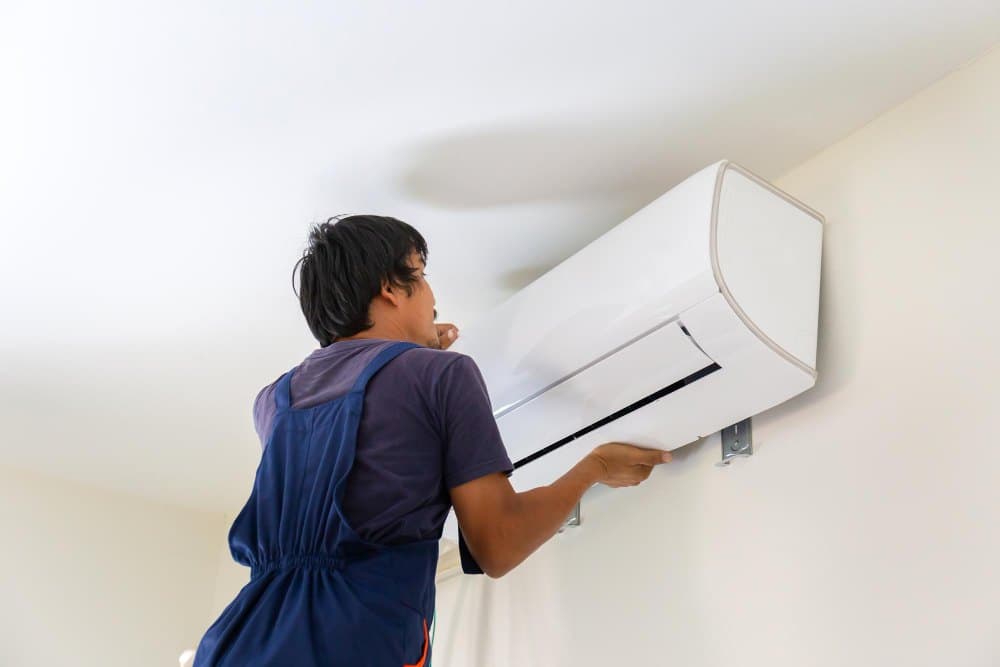 A technician fitting a wall-mounted indoor unit in a home.