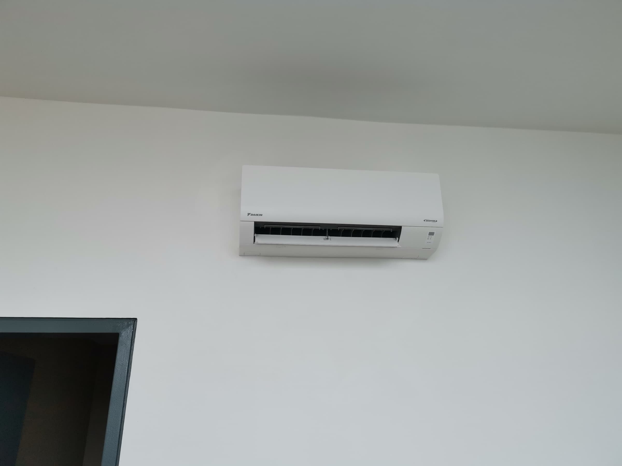 A Daikin inverter wall-mounted indoor unit fitted high on a plain wall in a finished home.