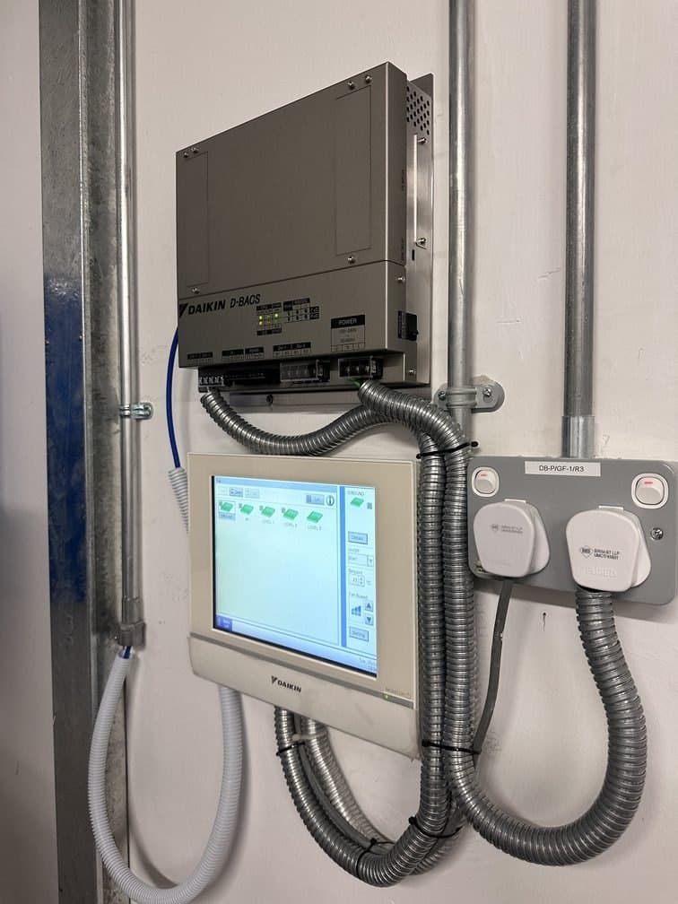 A Daikin centralised controller mounted in a plant area, wired into the building's system.