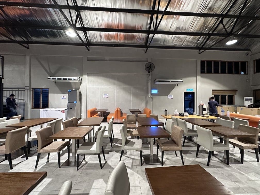 Cafeteria seating with wall-mounted units and a ceiling fan high on the wall behind.