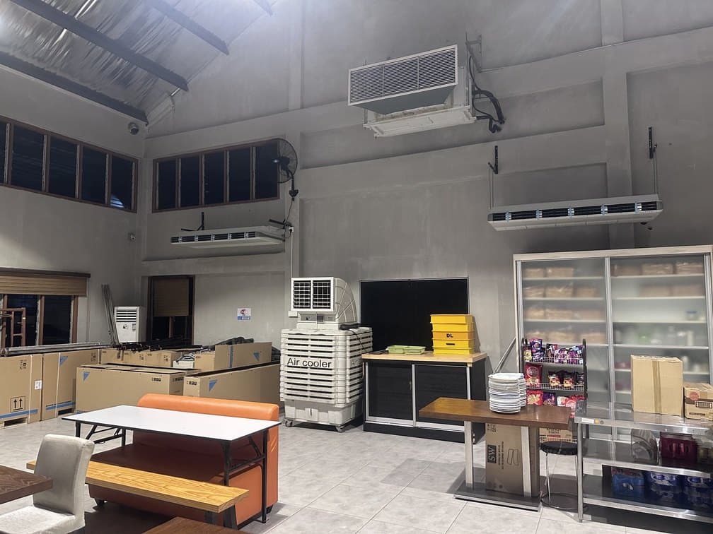 The servery end of the cafeteria with wall-mounted units installed high above the counters and a portable cooler below.