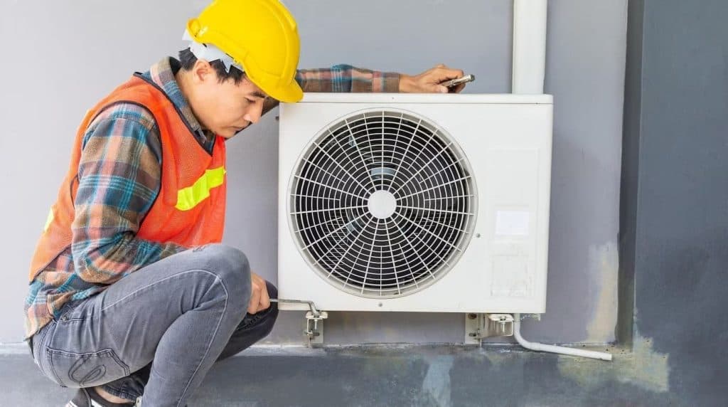 A technician assessing an old air conditioner for the needed repairs