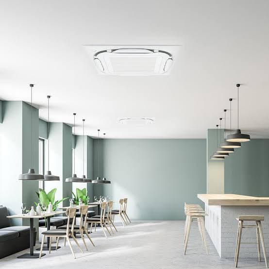 A dining room with two ceiling cassettes spaced across a flat white ceiling above the tables and counter seating.