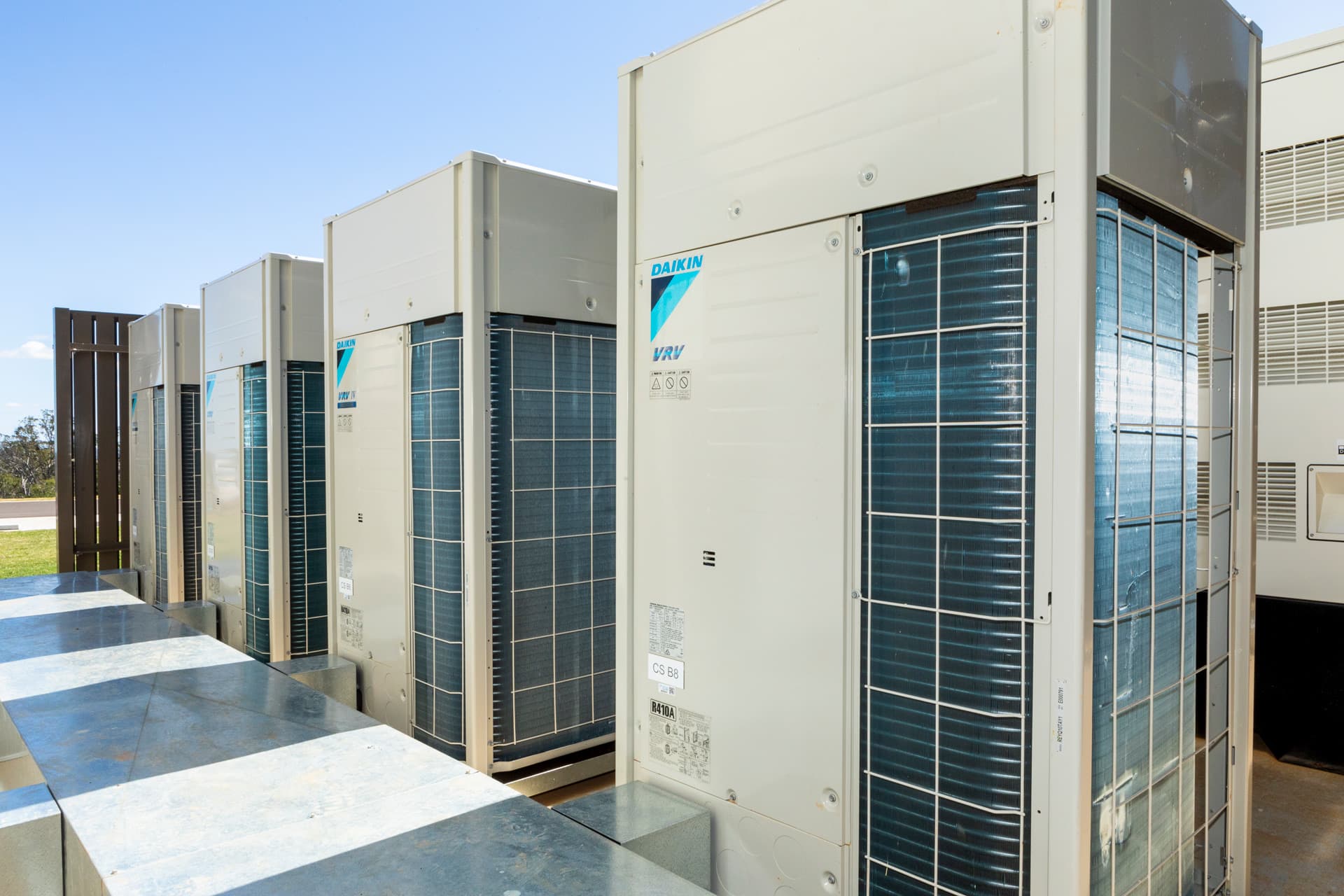 A bank of Daikin VRV IV condensing units standing in line on an outdoor plant deck.