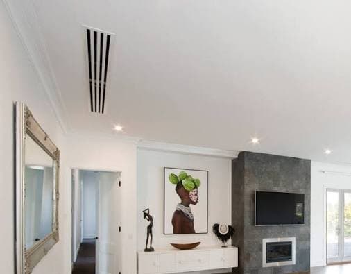 A living room ceiling with a narrow linear slot diffuser as the only sign of air conditioning.