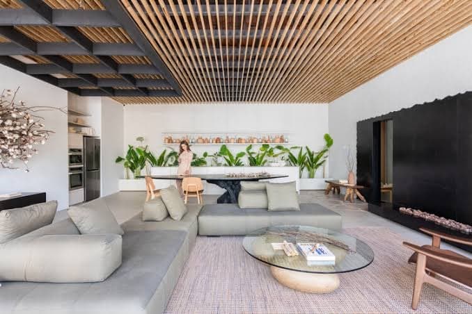 An open-plan living and dining room under a timber-slatted ceiling set within dark coffers, with no air-conditioning equipment in view.