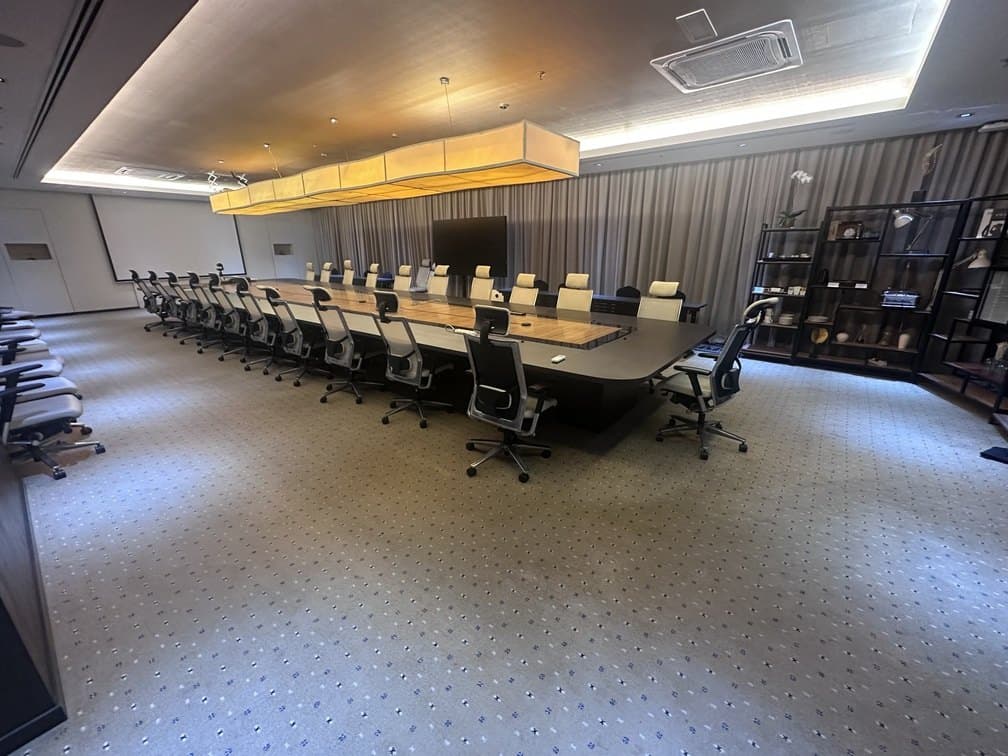 A long board room with a single conference table, ceiling cassettes set into the acoustic ceiling above.