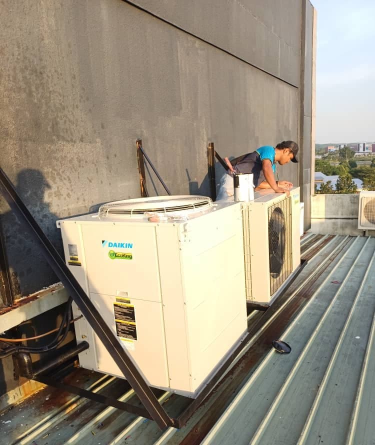 A technician working at a larger condensing unit on the roof deck.