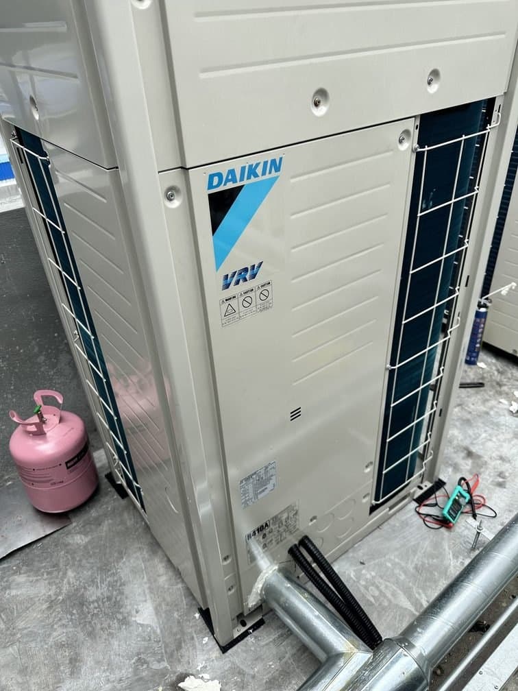 A Daikin VRV condensing unit standing on its plinth with charging equipment connected alongside.