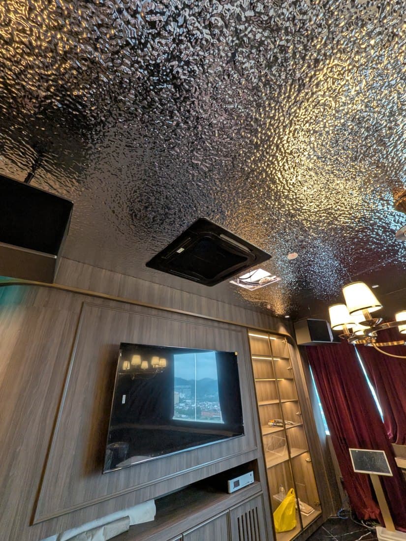 A ceiling cassette set into a heavily textured dark ceiling above a panelled lounge wall.