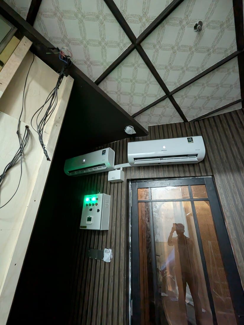 A wall-mounted split unit and a separate control enclosure beside the humidor's glazed door.