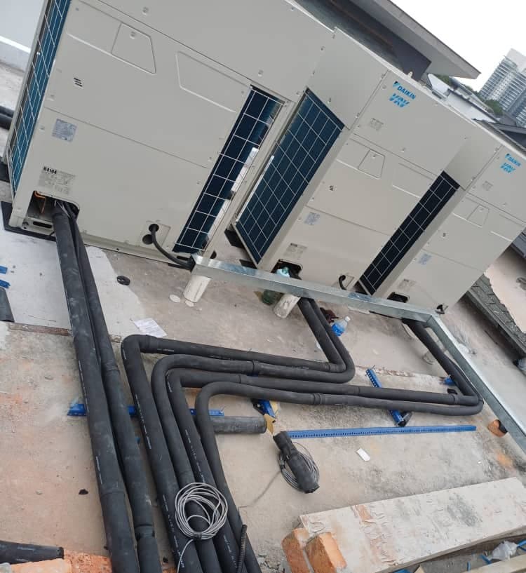 Insulated refrigerant lines and control cabling run across a flat roof toward the outdoor plant.