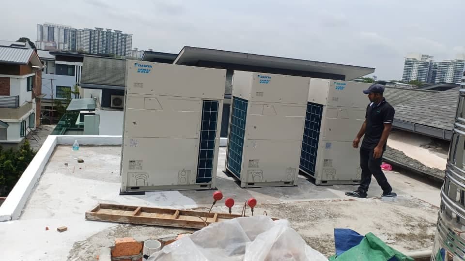 Three VRV condensing units installed side by side on a flat roof deck beneath a shade canopy.