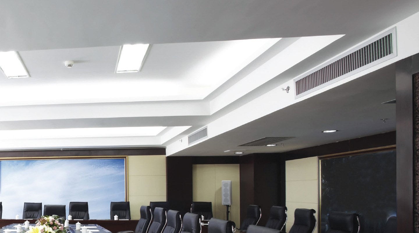 Linear supply grilles in the ceiling of a boardroom, the ducted units concealed above.